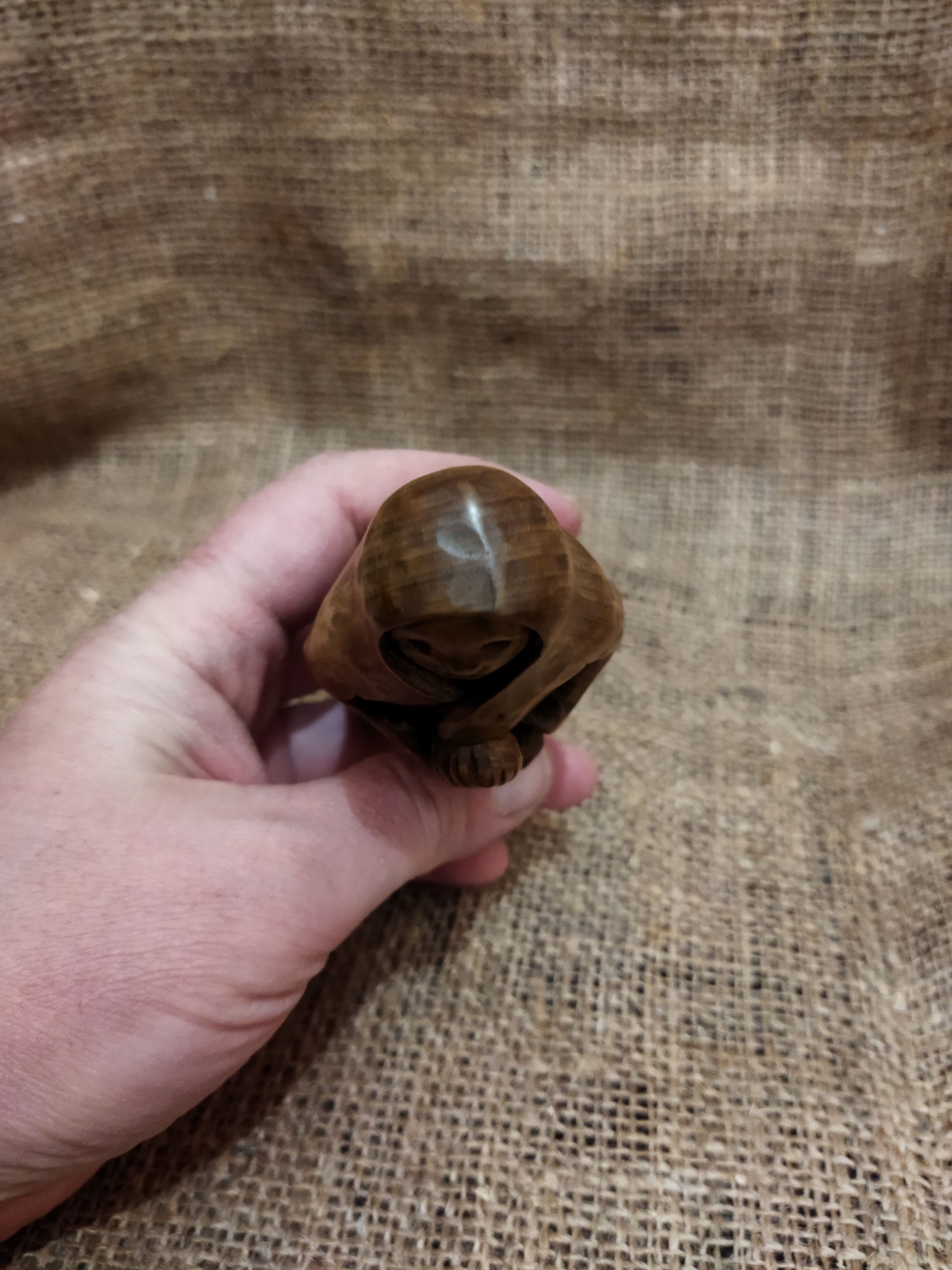 Hand-carved wooden statuette of the Slavic goddess Makosh, depicted with a serene expression, holding symbols of fate and abundance, set against a natural burlap background.